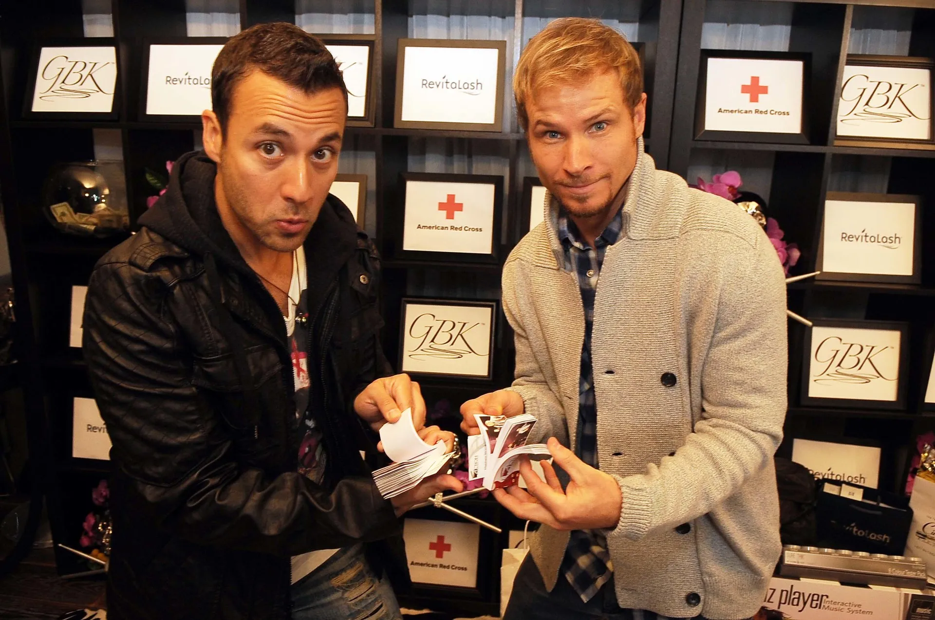 Two men are standing next to each other in front of a red cross display