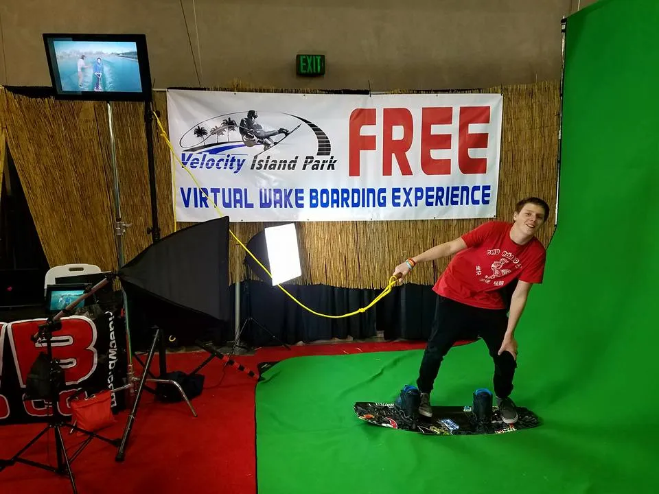 A guest riding a virtual wakeboard at a branded VR activation in front of a green screen
